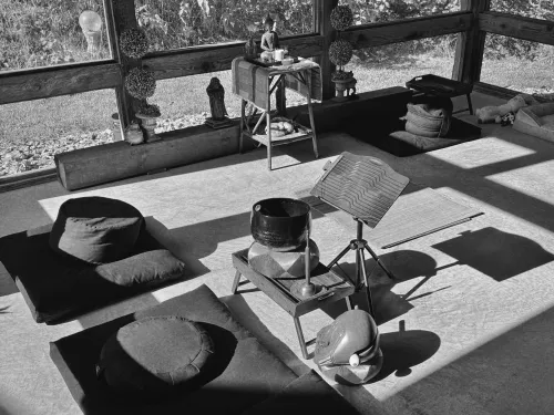Black and white photo of zafus, zabutons, Zen instruments, and a Buddha statue.